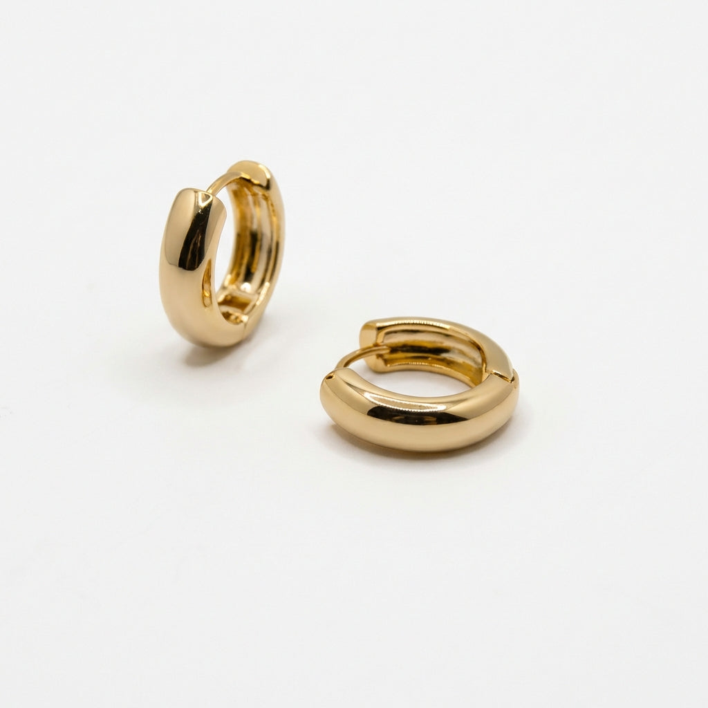 Pair of gold huggie earrings on white background