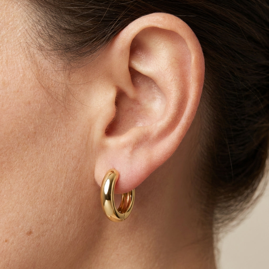 Model wearing gold huggie earrings showing scale