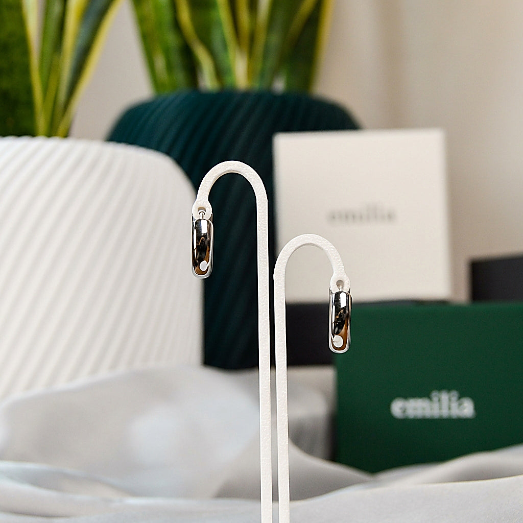 Pair of silver huggie earrings on white background