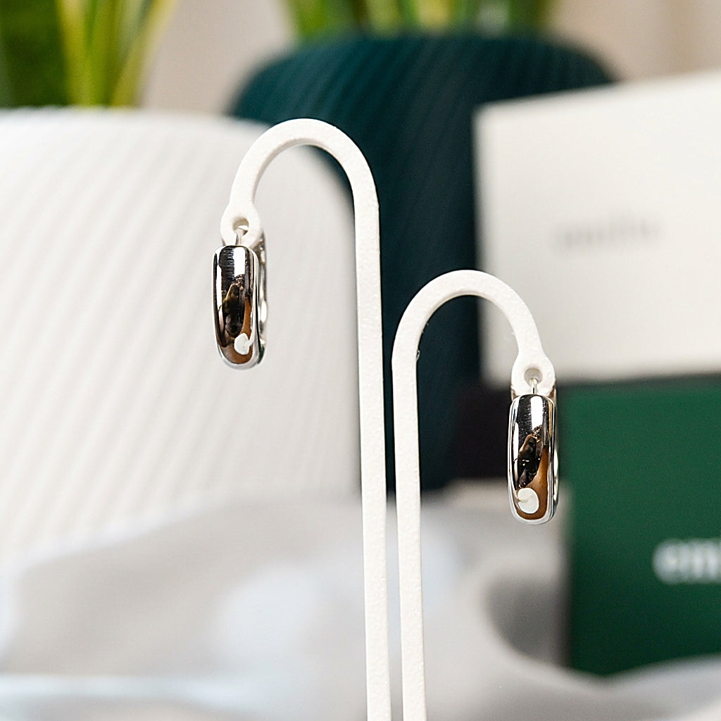 Pair of silver huggie earrings on white background