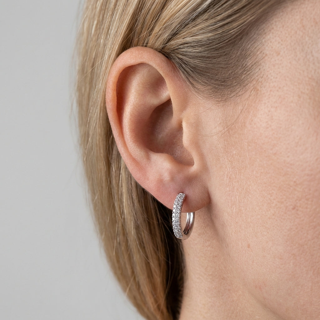 Model wearing silver huggie earrings showing scale