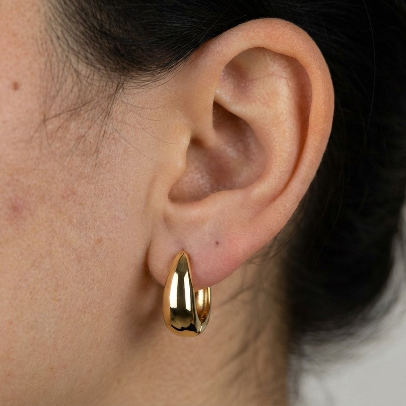 Model wearing gold hoop earrings showing scale