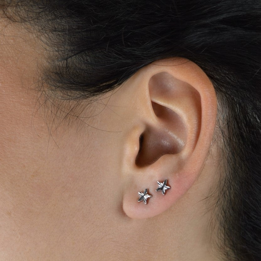 Model wearing silver stud earrings showing scale