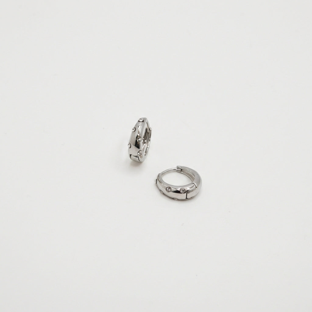 Pair of silver huggie earrings on white background