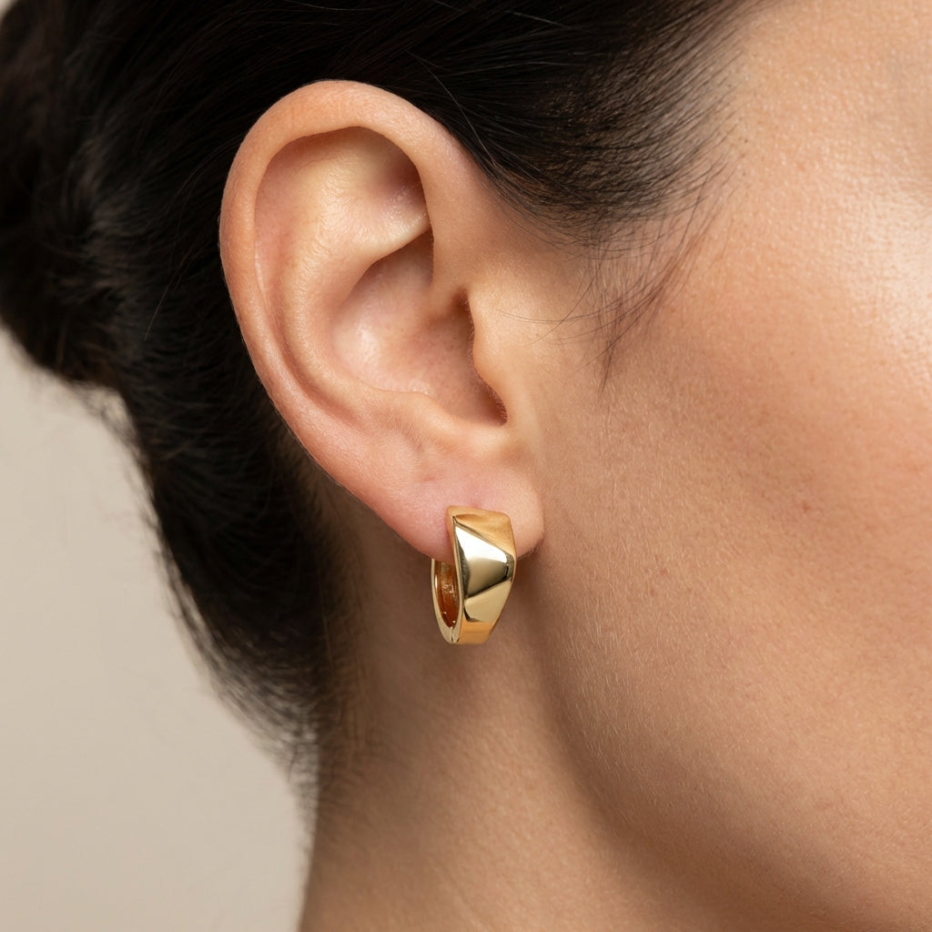 Model wearing gold huggie earrings showing scale