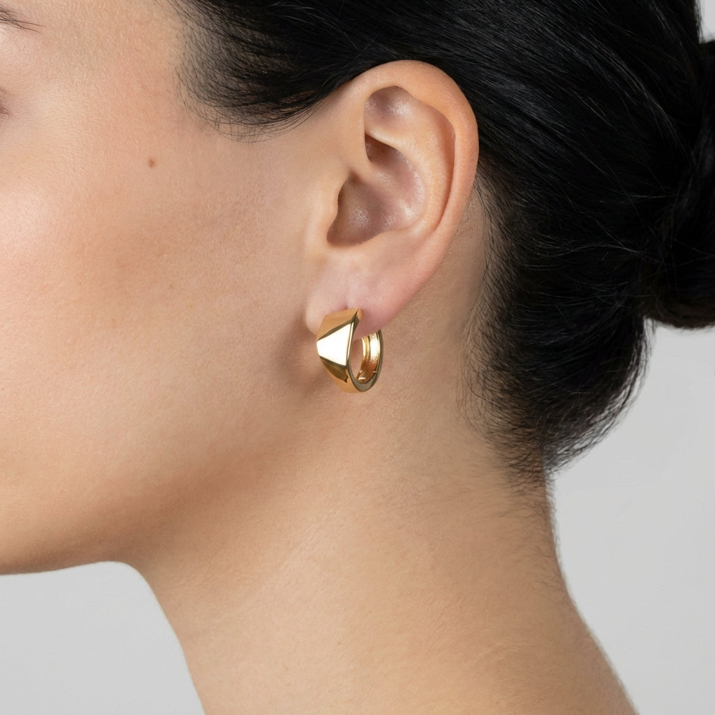 Model wearing gold huggie earrings showing scale