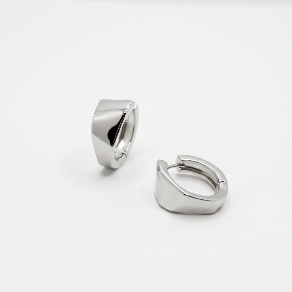 Pair of silver huggie earrings on white background