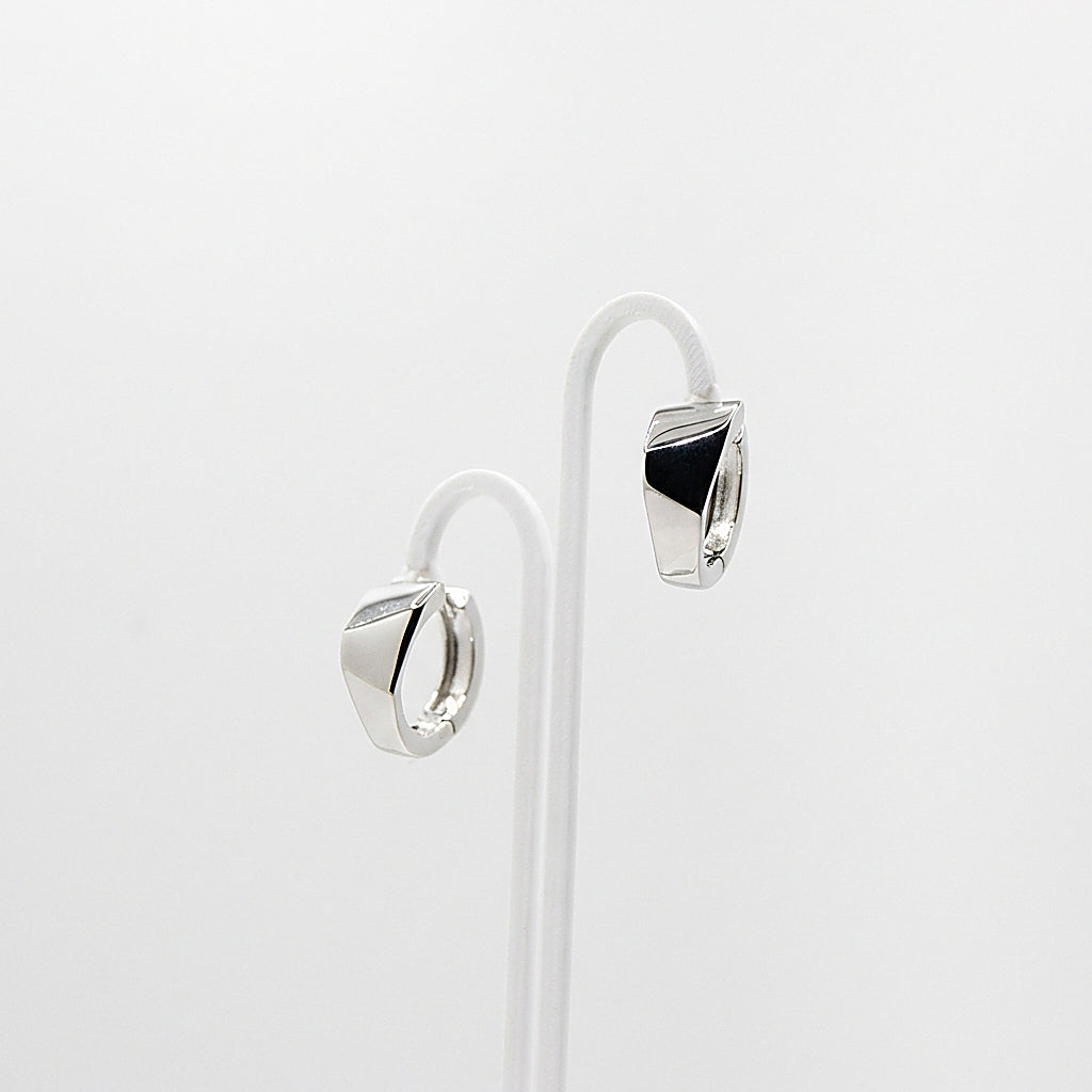 Pair of silver huggie earrings on white background