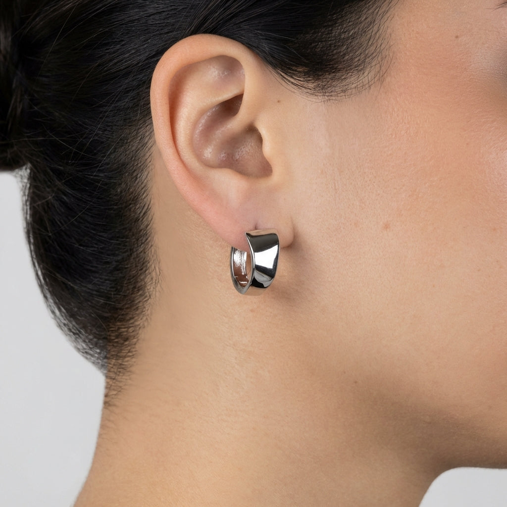 Model wearing silver huggie earrings showing scale